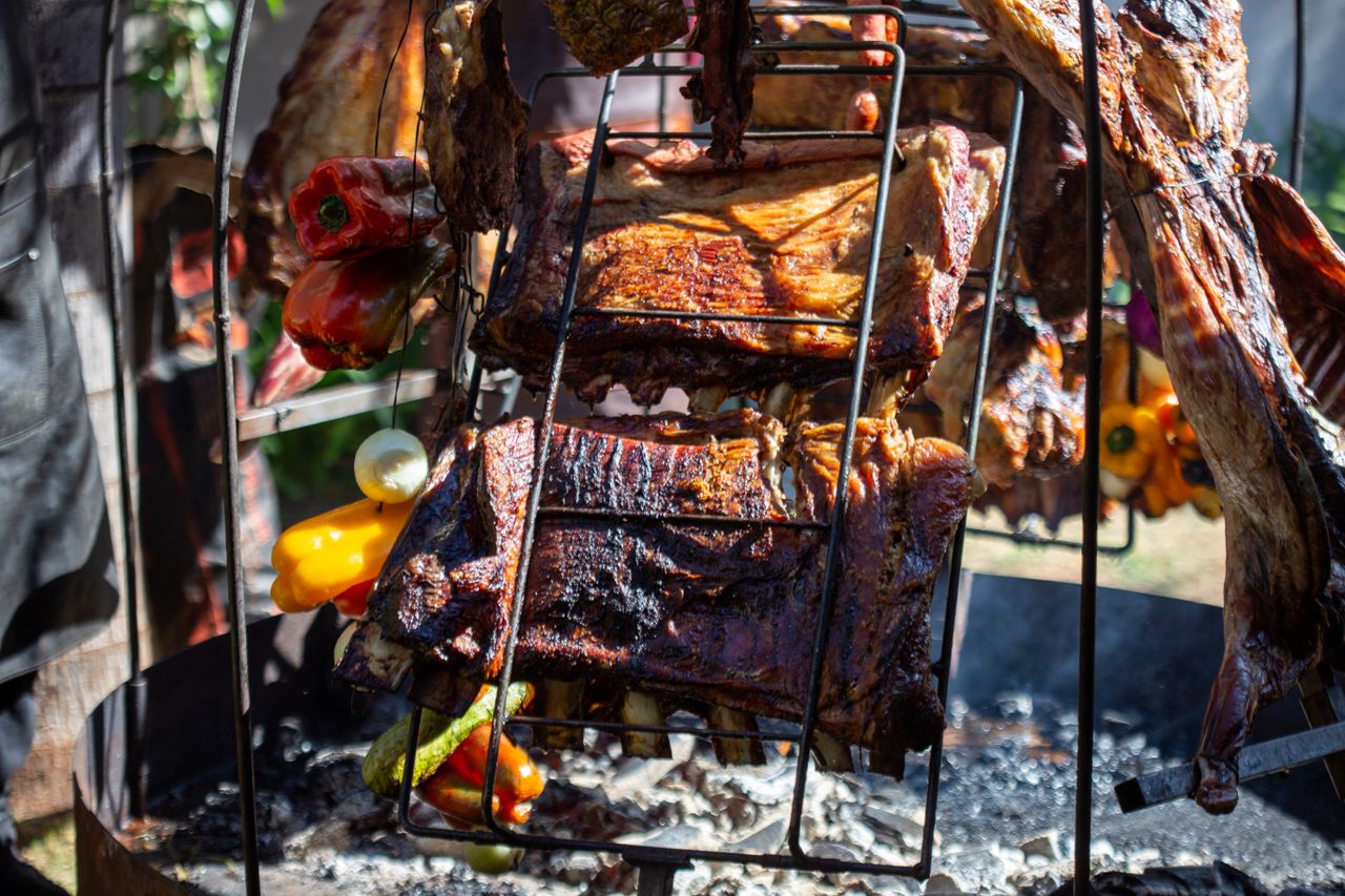 Close-up of roasted ribs and vegetables on an outdoor barbecue grill.