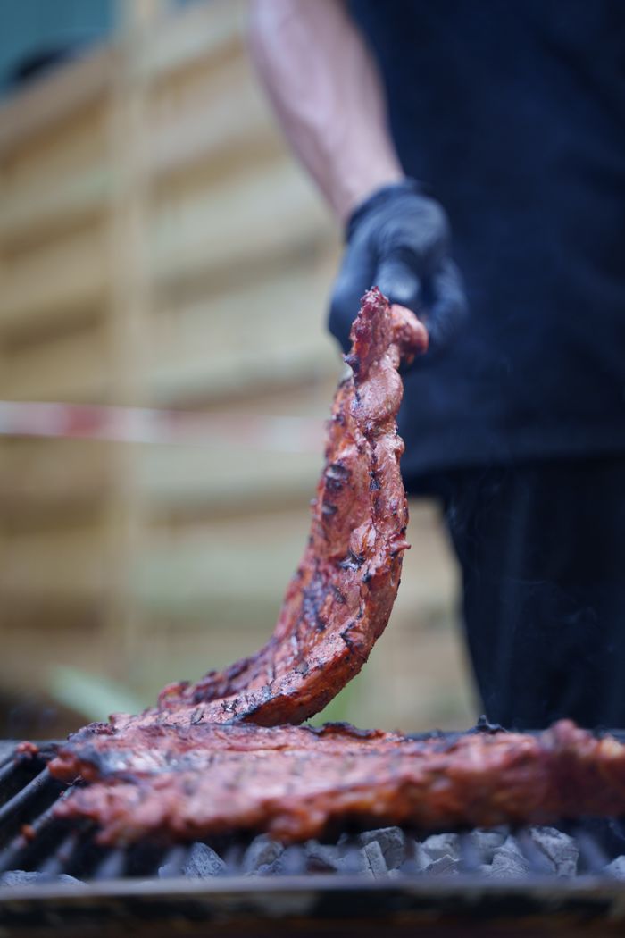 A mouth-watering close-up of ribs being grilled outdoors, showcasing a classic barbecue scene.