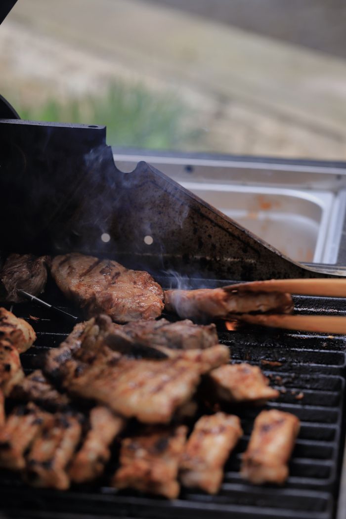 Close-up of delicious meat grilling on an outdoor barbecue with smoke rising, perfect for summer cooking themes.