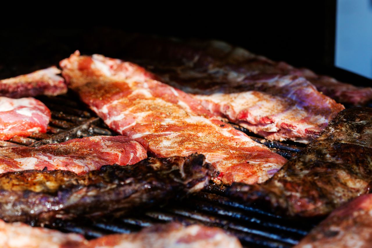 Close-up of seasoned and cooked ribs sizzling on a grill, perfect for a barbecue meal.